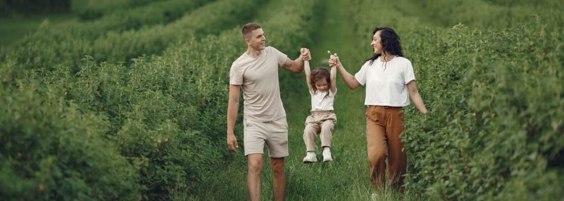 A happy family walking in a lush, green rural field together.