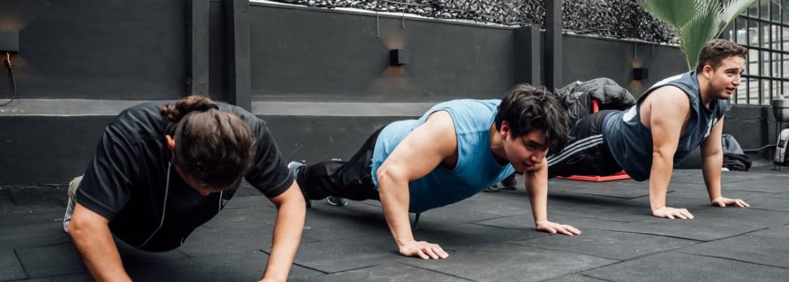 Men performing push-ups during a group workout session in Mexico City gym.